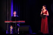 Na scenie prowadząca koncert Barbara Pakura-Brzoska, ubrana w ciemno czerwoną suknię wieczorową…