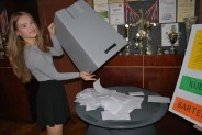Uczennica opróżnia pojemnik z kartkami do głosowania