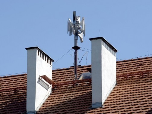 Syrena alarmowa na spadzistym dachu, widoczna między dwoma białymi kominami na pierwszym planie