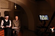 Dwoje aktorów w strojach scenicznych czyta tekst sztuki w pomieszczeniu piwnicznym. Na zdjęciu…